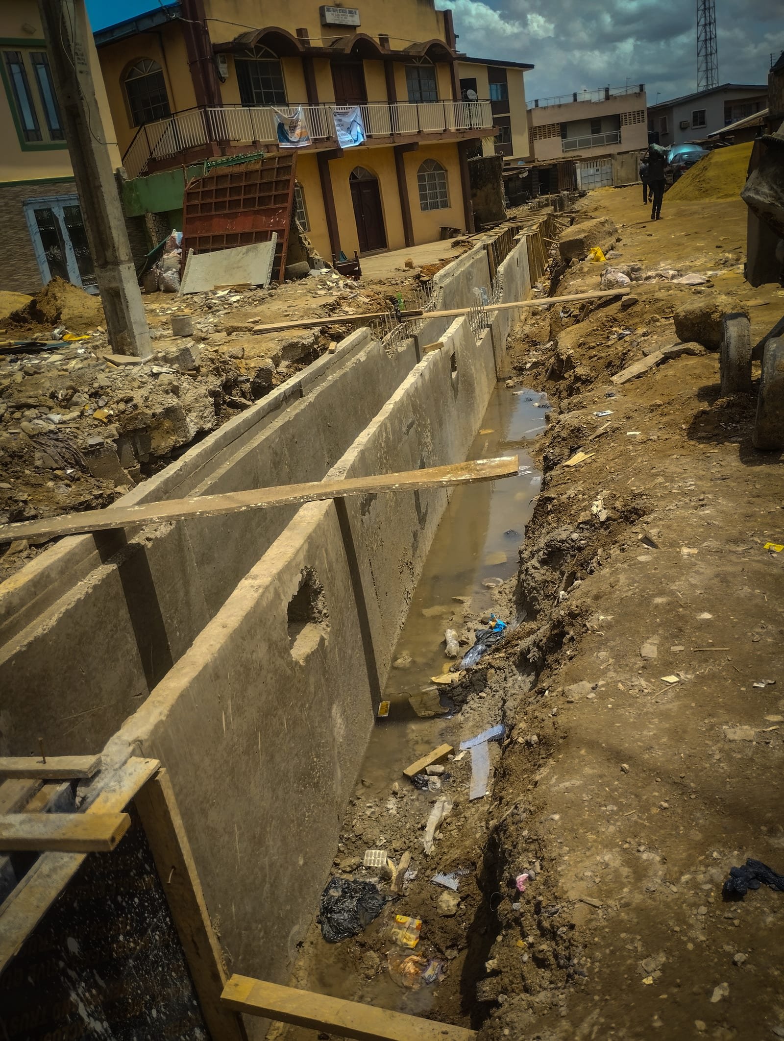 A concrete drainage channel under construction beside houses