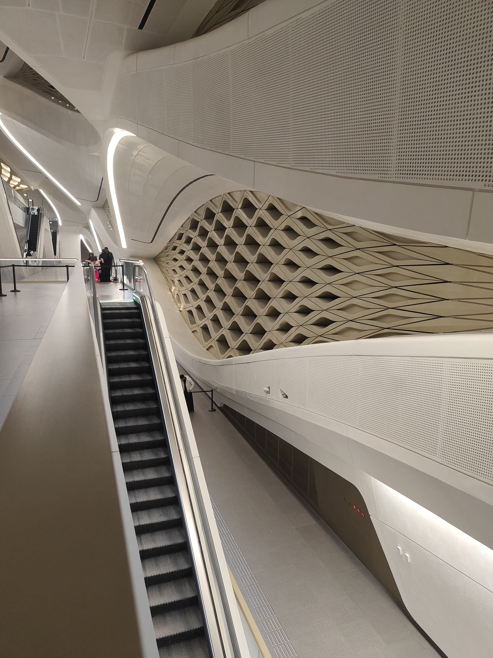 Interior of a Riyadh metro station with a curved wall and an escalator.